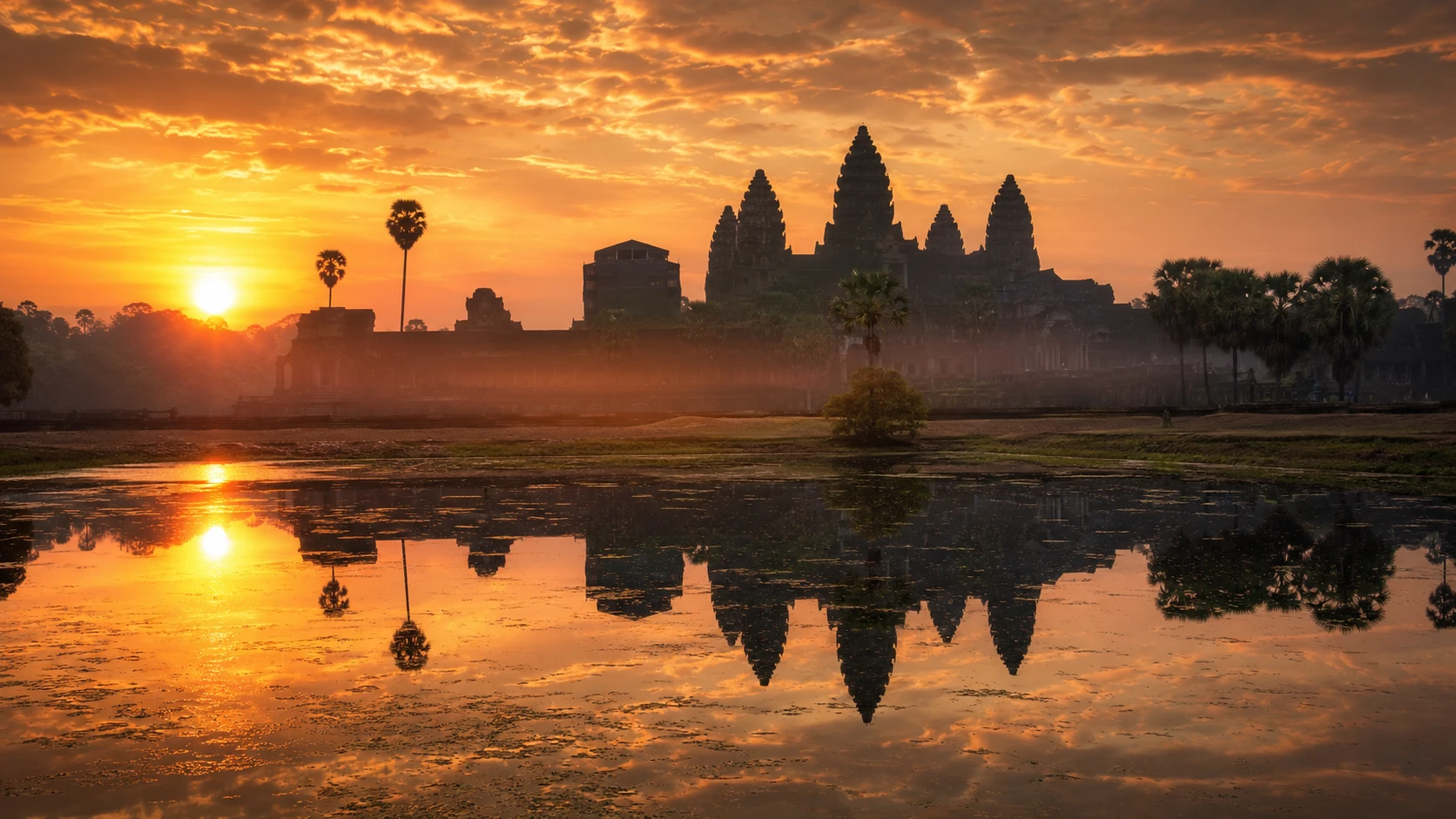 Angkor Wat silhouetted and reflected in the moat at sunrise, Cambodia